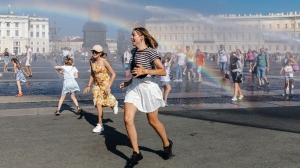 Петербуржцы спасаются от жары под струями поливальных машин на Дворцовой площади