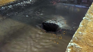 По Октябрьской набережной на проезжую часть откуда-то течет холодная вода